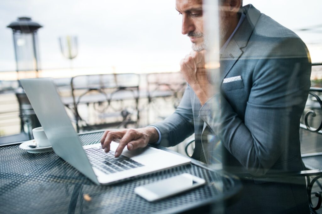mature businessman with laptop outside a cafe